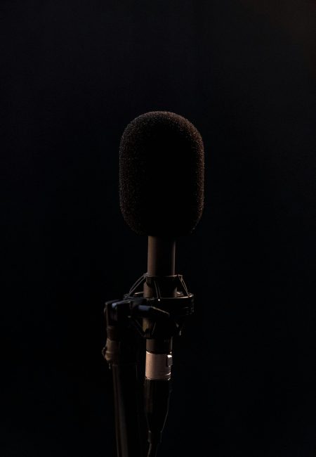 Close-up of a black microphone in a studio setting, isolated on a dark background.